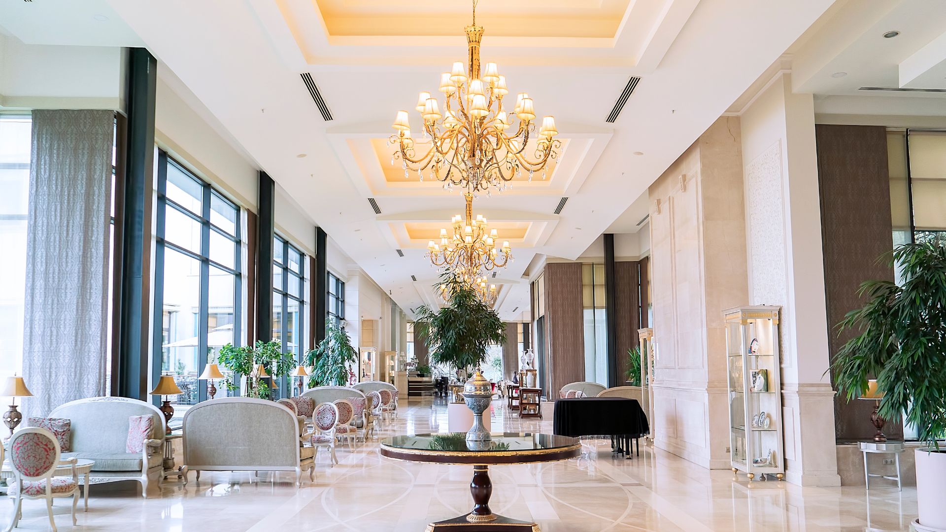 Elegant hotel lobby with chandeliers, plush seating, and large windows