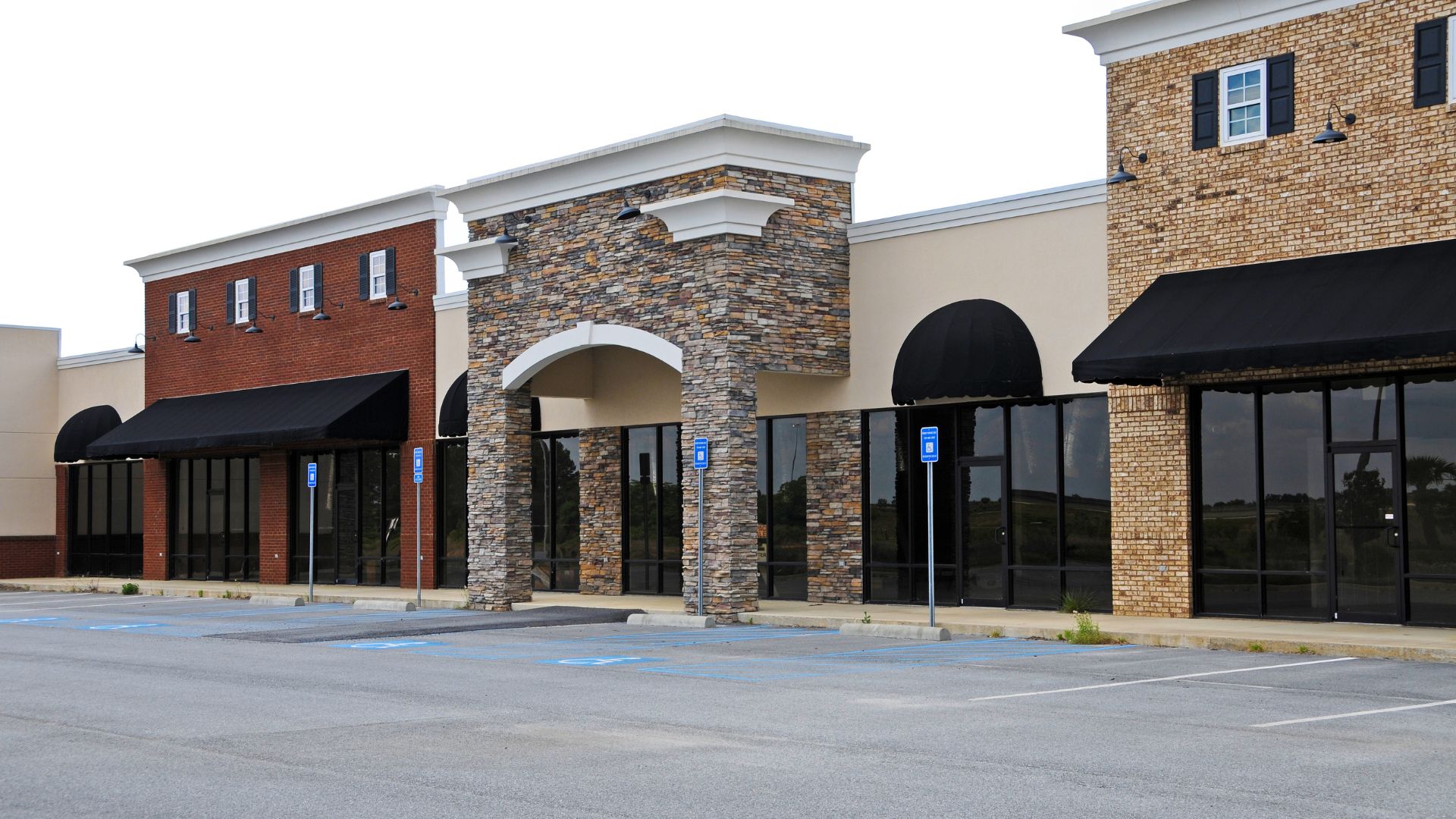 Empty strip mall with brick and stone facades and black awnings