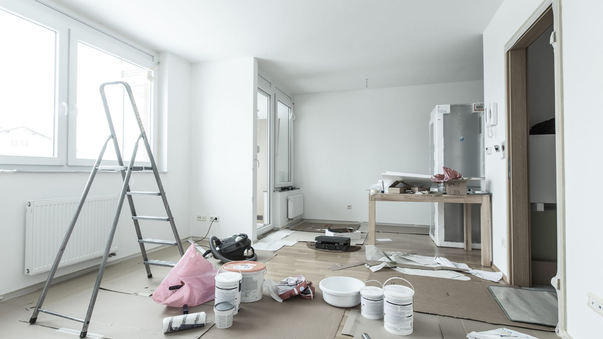 Room under renovation with ladder, paint supplies, and construction materials