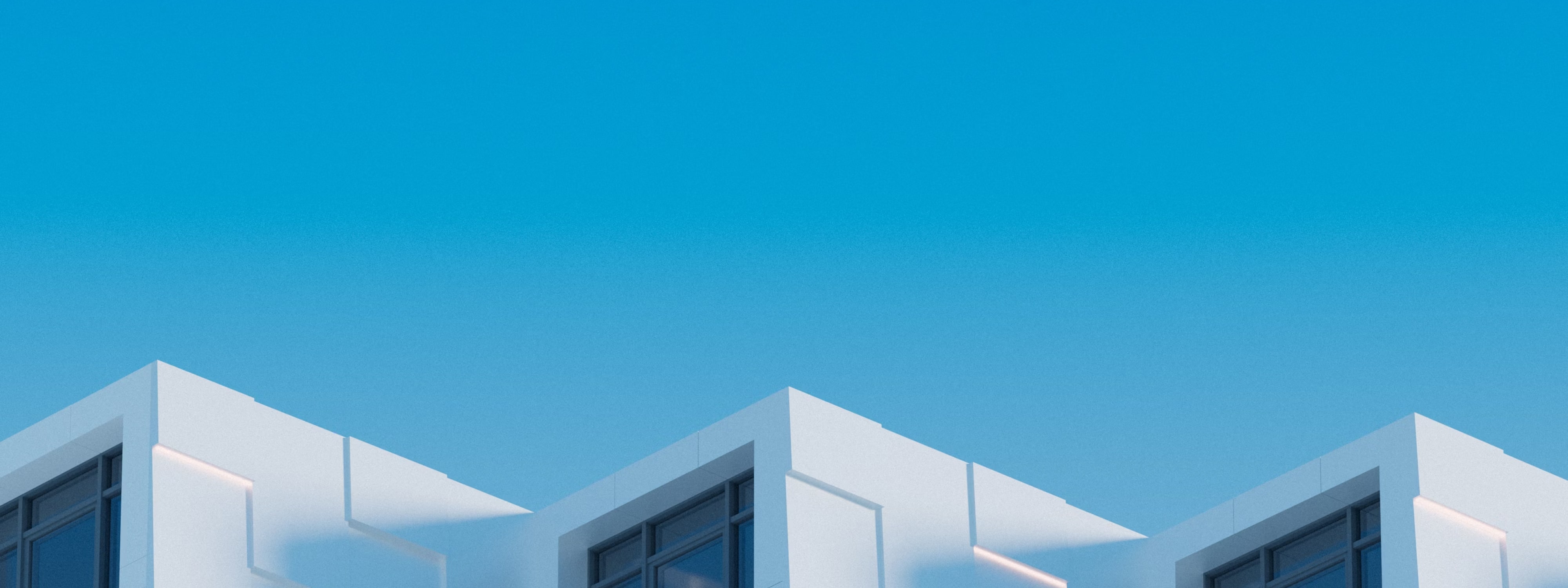 White modern building facades against bright blue sky with geometric windows