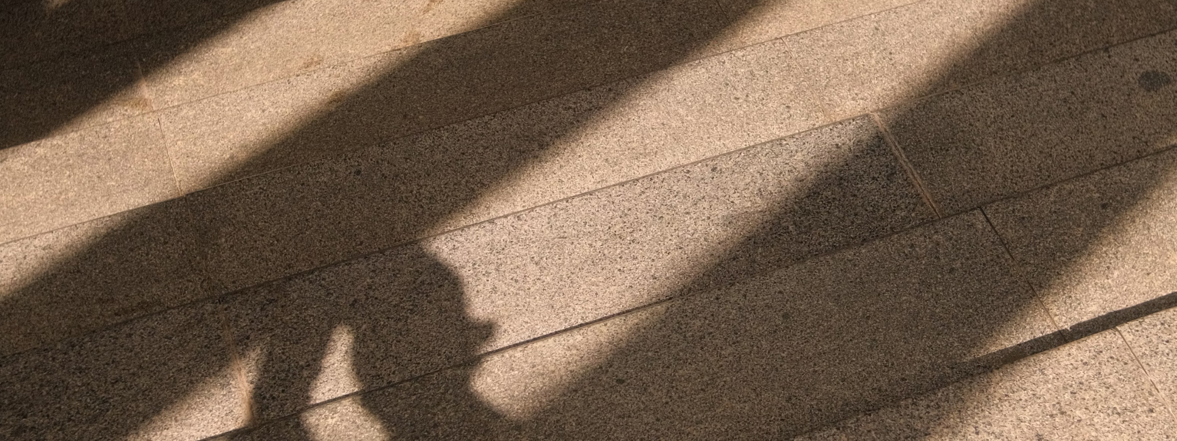 Shadows cast on textured tile or stone floor with diagonal light